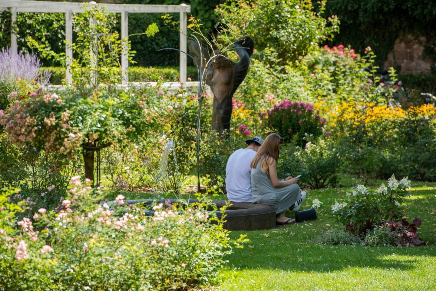 Ein Pärchen sitzt auf Steinen im blühenden Rosengarten