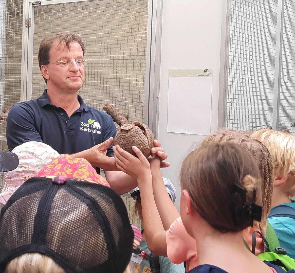 Zoo-Chef Reinschmidt mit einem Gürteltier, das von den Ministudenten der EKSA nagefasst wird. 